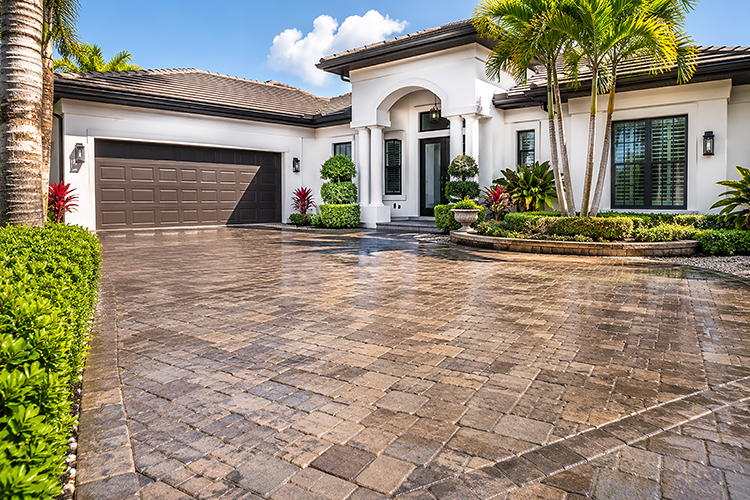 Clean paver driveway and bright white stucco exterior of a Florida luxury home, showcasing multiple surfaces that benefit from professional soft wash cleaning