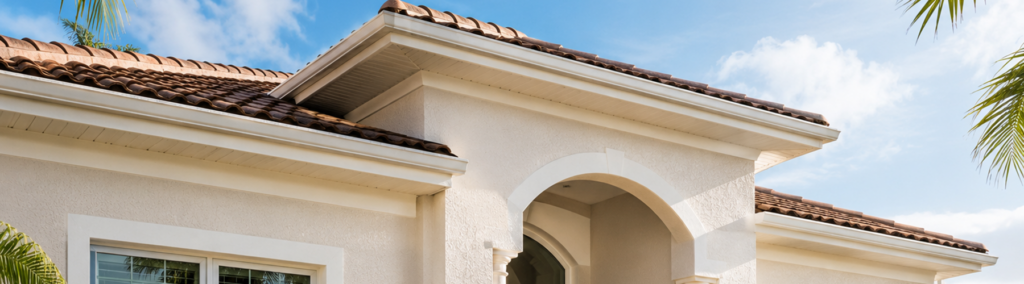 Light stucco home exterior with terracotta roof tiles in Stuart, FL, showing the type of surface that benefits from professional soft washing services.