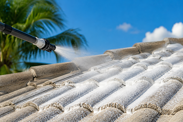 Professional applying low-pressure soft wash to concrete roof tiles in Florida, using controlled water flow to safely clean without cracking or displacing tiles.